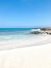 Scenic view of beach against clear blue sky