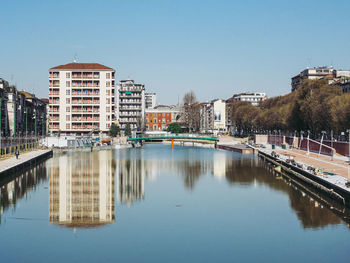 Reflection of buildings in city against clear sky