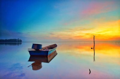 Boat moored on sea against sky during sunset