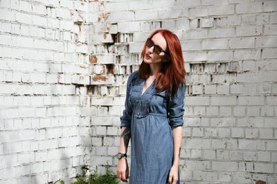 Young woman standing against brick wall