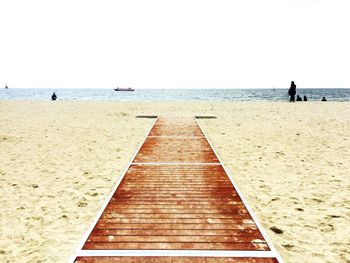 Boardwalk at beach against clear sky