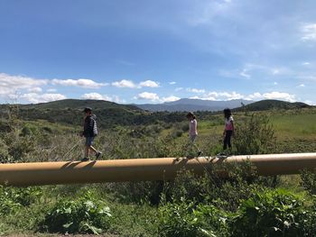 Rear view of people walking on landscape against sky