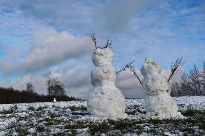 White sculpture on snow covered plants against sky