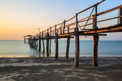 Pier over sea against sky at sunset