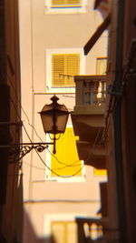 Low angle view of yellow lamp hanging on building