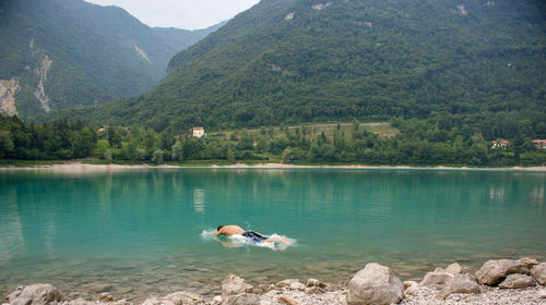 Man swimming in lake against mountains