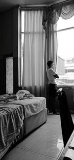 Rear view of man relaxing on bed at home