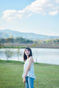 Young woman standing against lake