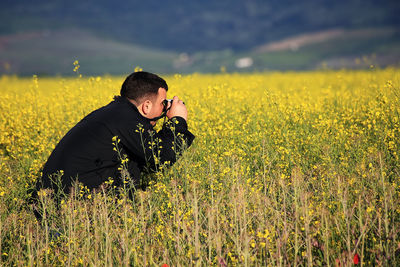 Full length of young man looking at sunflower field