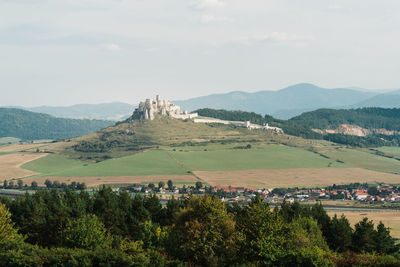 Scenic view of townscape by mountain against sky