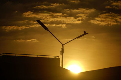 Low angle view of silhouette crane against sky during sunset