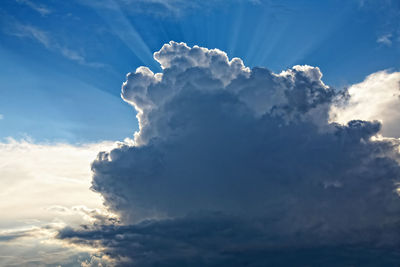 Low angle view of sunlight streaming through clouds