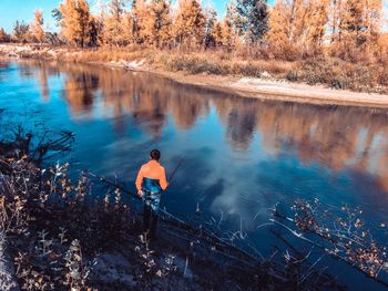 Rear view of man on lake by trees