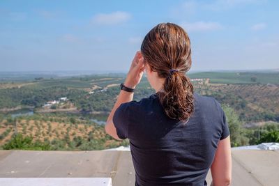 Rear view of woman looking towards landscape against sky