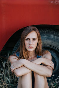 Portrait of a beautiful young woman sitting against red wall