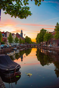 Scenic view of lake and buildings against sky during sunset