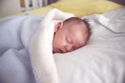 Cute baby boy sleeping on bed at home