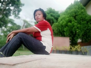 Young woman looking away while sitting on tree