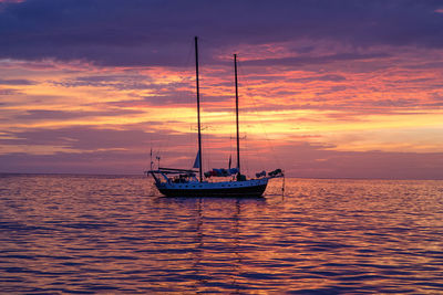 Sailboat sailing in sea at sunset