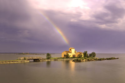 Scenic view of rainbow over sea and buildings against sky