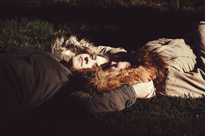 Portrait of young woman lying down on field