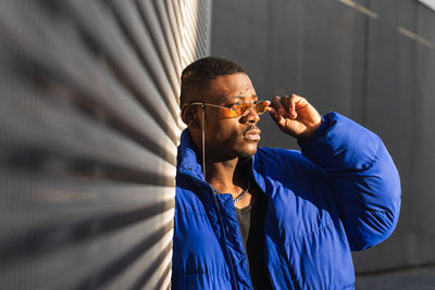 Portrait of young man standing against blue wall