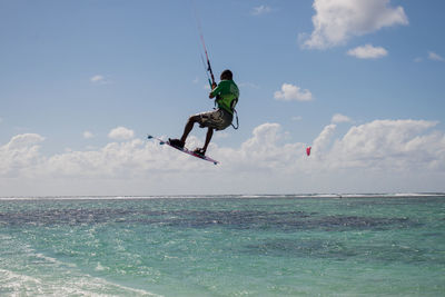 Man kiteboarding in sea against sky