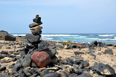 Stack of pebbles on beach against sky