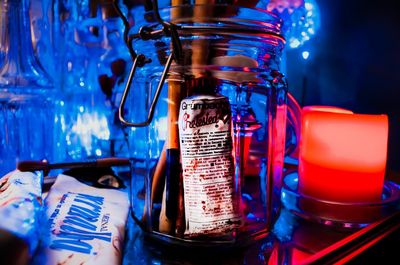 Close-up of jar by illuminated object on table