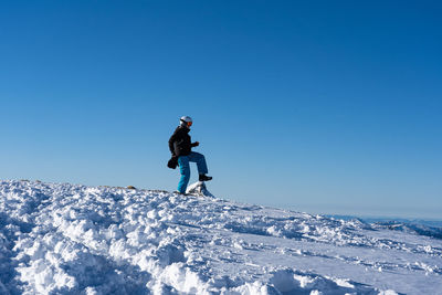 Man on snowcapped mountain against clear blue sky