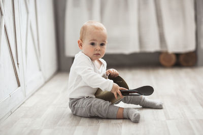 Baby son playing on the floor with kitchen utensils in a real bright interior, lifestyle style.