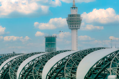 Passenger airplane flying above airport building. the airport building and air traffic control tower
