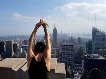 Rear view of man looking at cityscape against sky