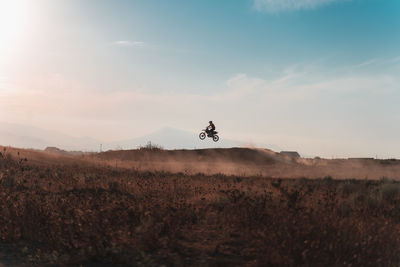 Man riding motorcycle on field against sky