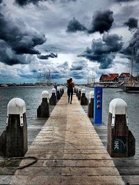 Rear view of people on pier over sea against sky