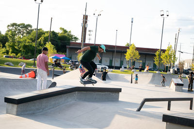 Group of people skateboarding in city against sky