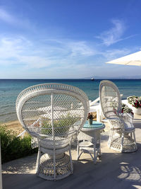 Chairs by sea against sky