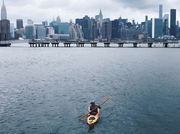 People on river against buildings in city