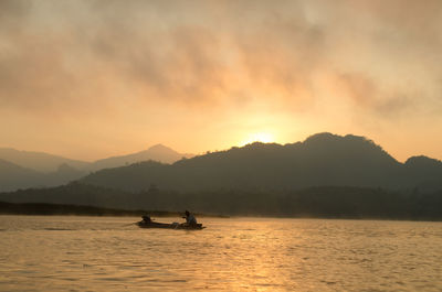 Silhouette man on boat against sky during sunset