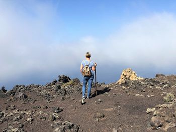 Man standing on rock against sky