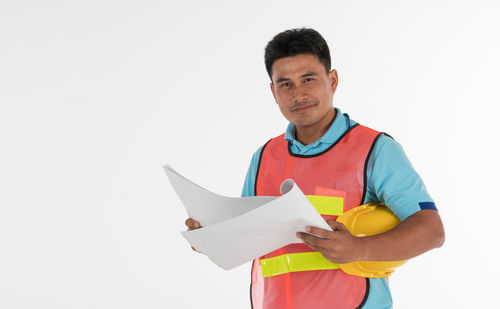 Portrait of man holding paper against white background