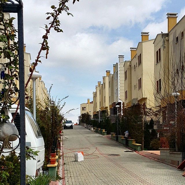 building exterior, architecture, built structure, street, city, street light, the way forward, sky, road, tree, transportation, residential building, incidental people, car, day, building, residential structure, outdoors, city street, diminishing perspective