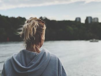 Rear view of woman looking at lake against trees