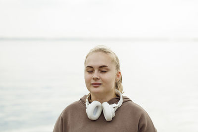 Young woman with eyes closed meditating in front of sea