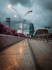 Illuminated street amidst buildings against sky at dusk