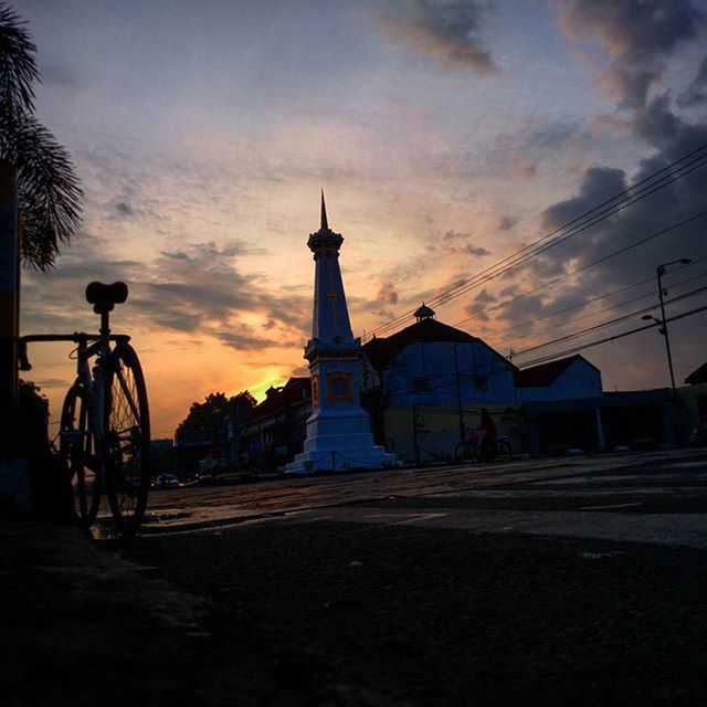 sky, sunset, architecture, building exterior, built structure, cloud - sky, transportation, land vehicle, bicycle, street, mode of transport, road, cloud, silhouette, cloudy, car, dusk, city, orange color, parked