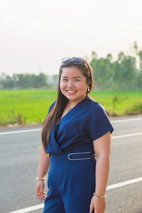 Portrait smiling asian woman in blue casual wear standing in front of rice field