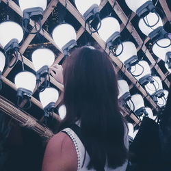 Rear view of woman touching lighitng equipment