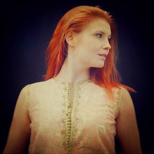 Portrait of young woman standing against black background