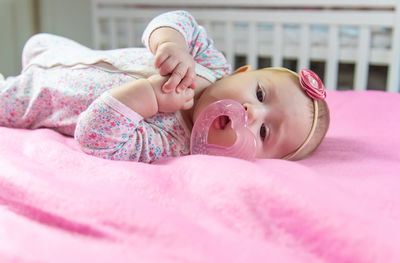 Portrait of cute baby lying on bed at home